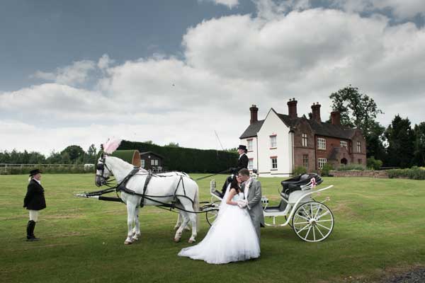 Bride and Groom with a horse and carriage in teh grounds of Heart of England Conference & Events Centre