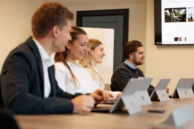 People in a meeting sat at a desk using Microsoft Surface devices