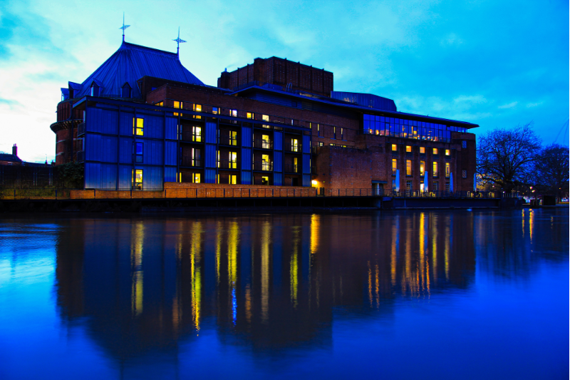 The lights of a building reflected in the river at dusk