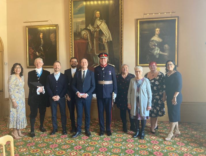 Lawrence Kelly (fifth from left) holding his British Empire medal next to Lord Lieutenant Tim Cox and family and friends.