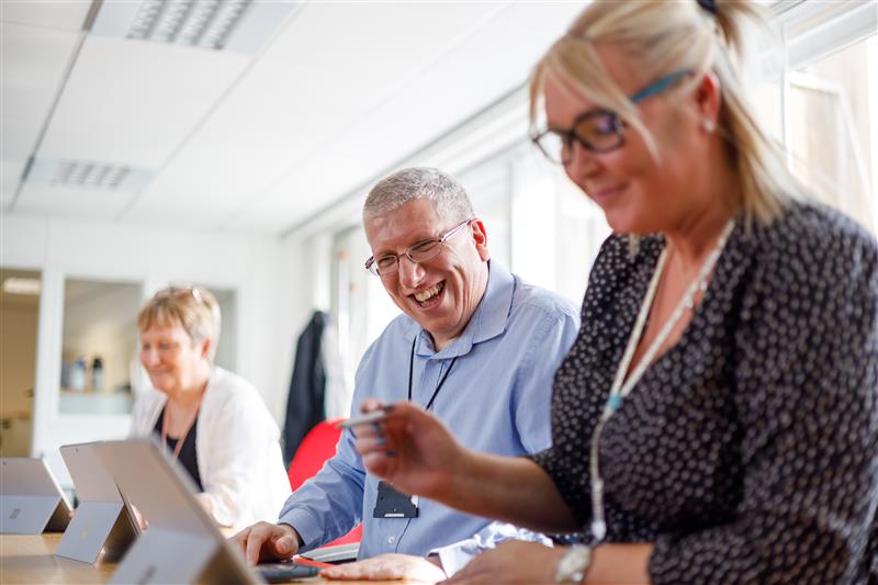 An image of 3 people working together on computers