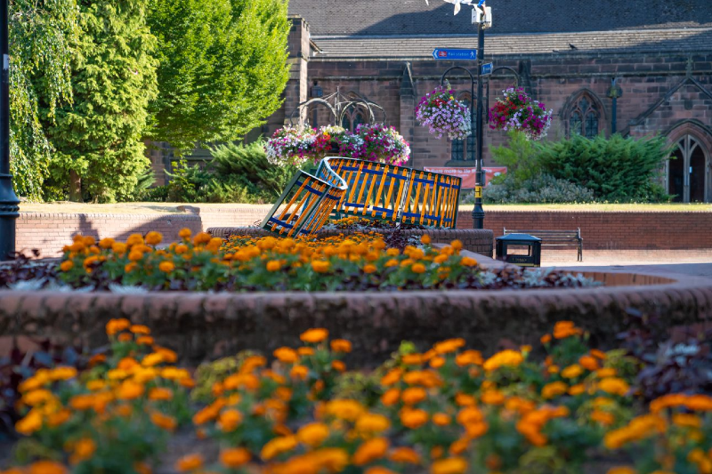 strip of orange flowers out of focus in front of a metal structure in the same colour orange