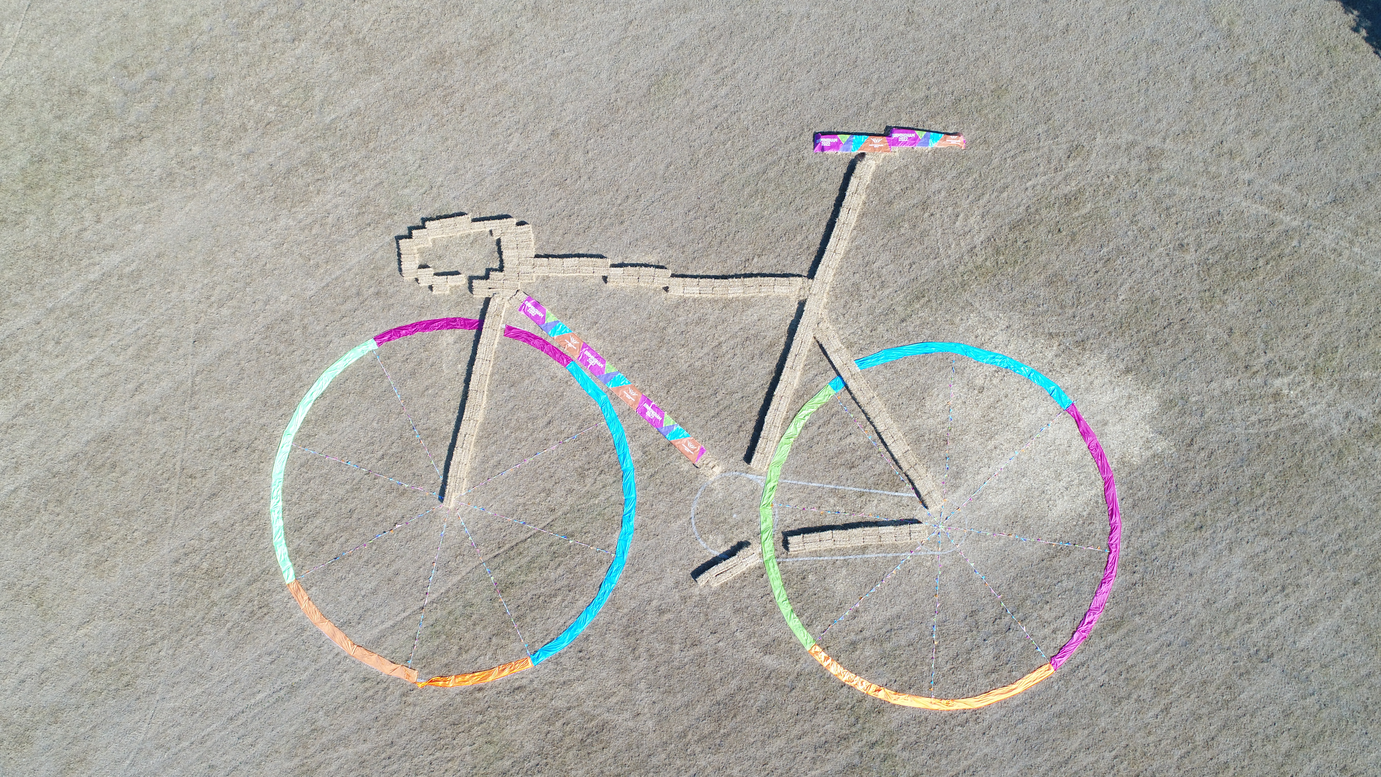 Straw and brightly coloured material arranged in the image of a bike