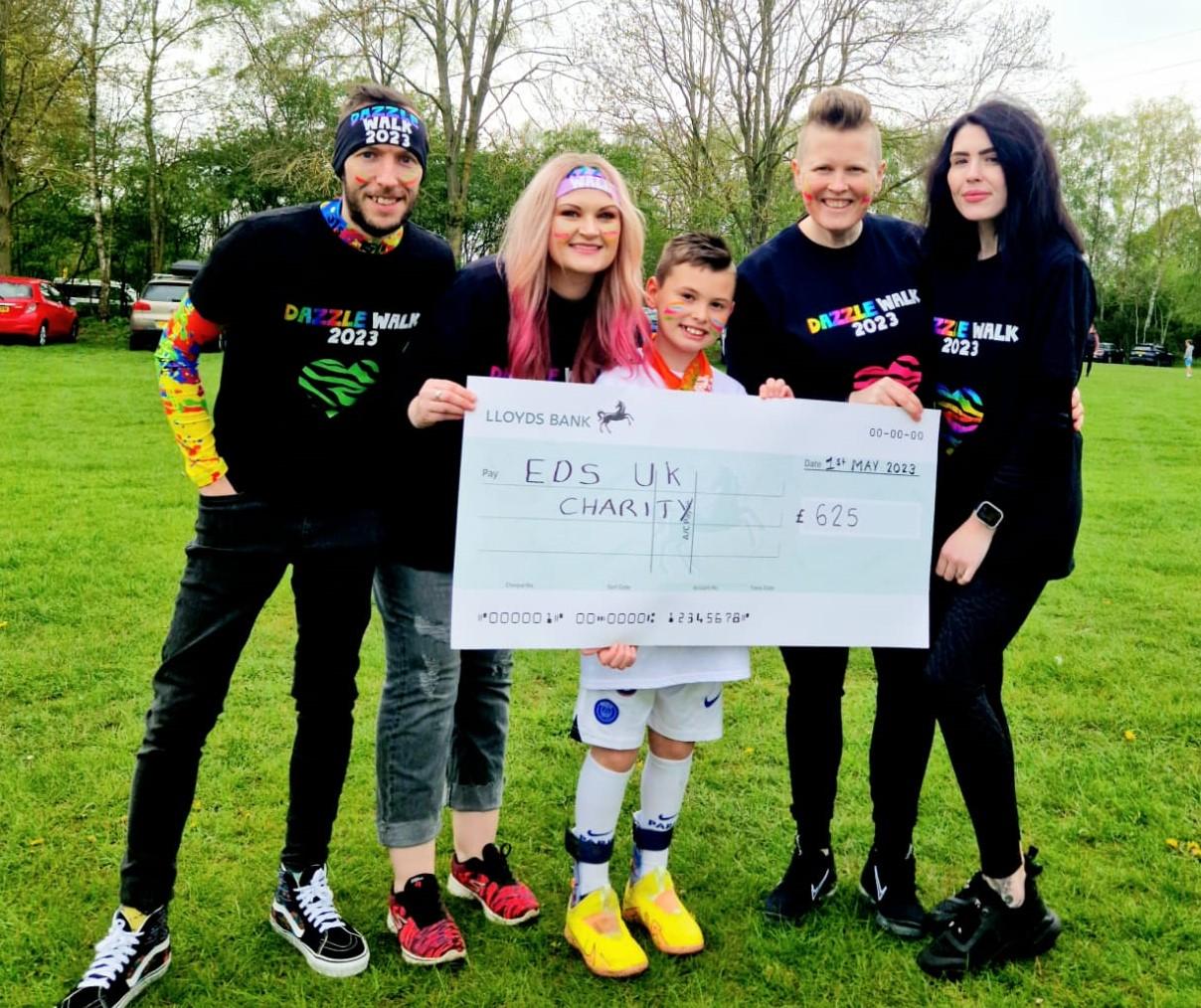 10-year-old Vinnie with friends and family holding a large cheque for £625
