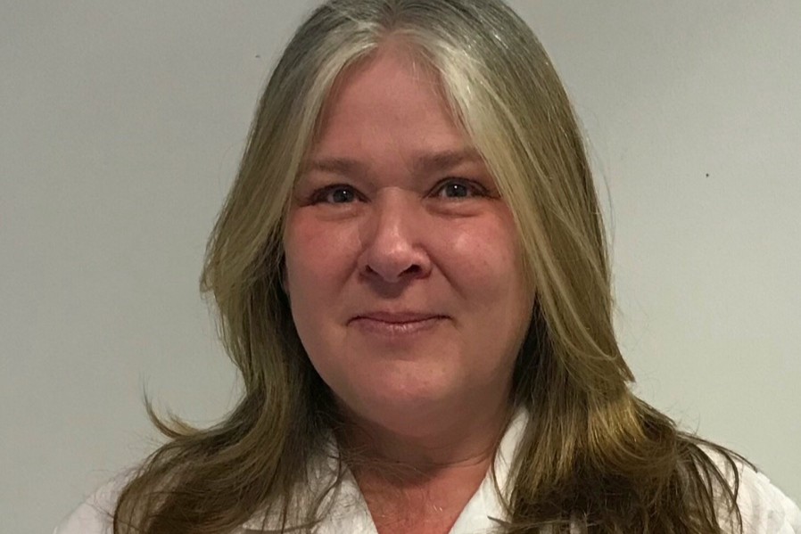 Deborah smiling at the camera in front of a plain background