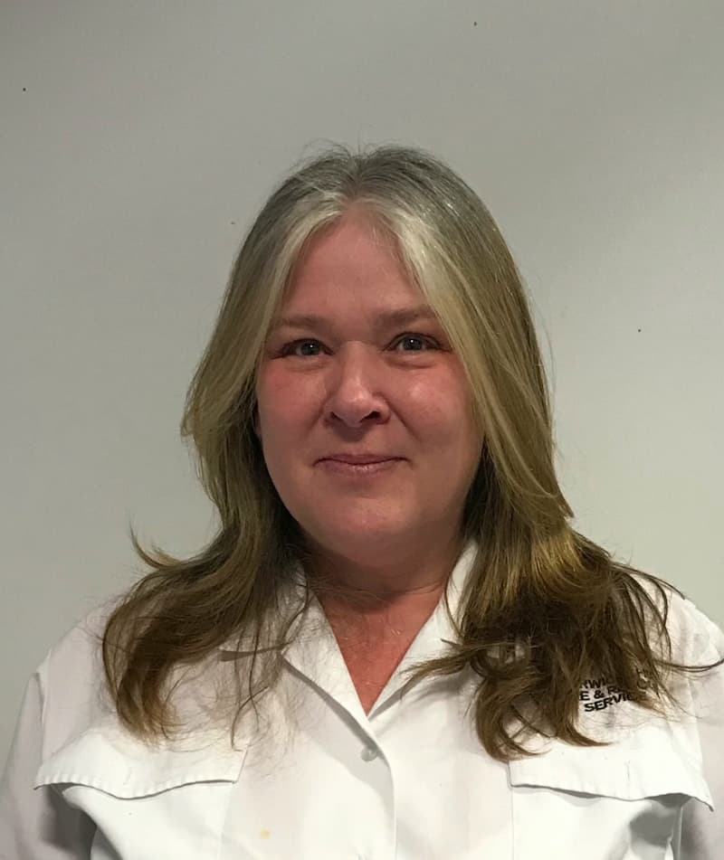 Deborah smiling at the camera in front of a plain background