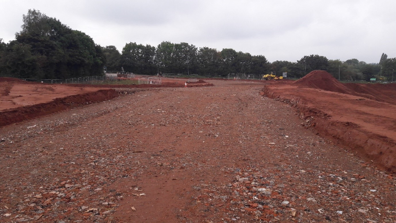 Photograph showing new road construction, particularly the capping (rock) foundation on which the road surface will be laid.