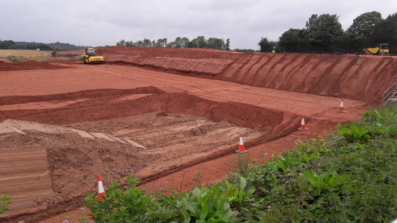 Depicting construction vehicles creating and filling in earthworks to support the construction of the new junction