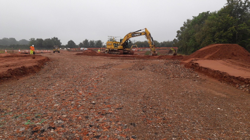 Photograph showing new road construction, particularly the capping (rock) foundation on which the road surface will be laid.