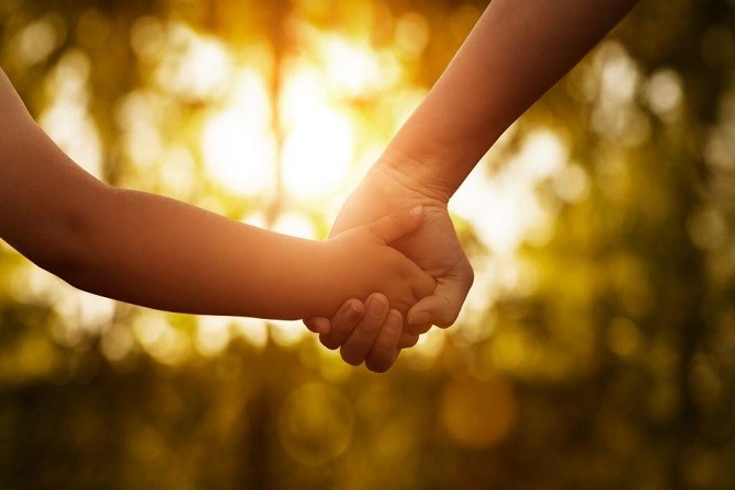A carer and child holding hands