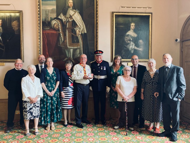 Douglas Shorter (centre) being presented with his British Empire Medal by Lord Lieutenant Tim Cox, alongside family and friends.