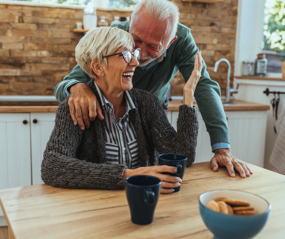 Two people, one who cares for the other are hugging  in a kitchen.