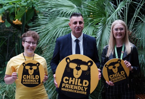 Jess, Reece and Abbey smiling at the camera holding CFW logos