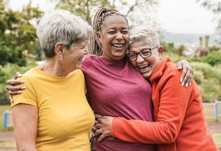 Three women who are carers embrace for Carers Rights Day 23.