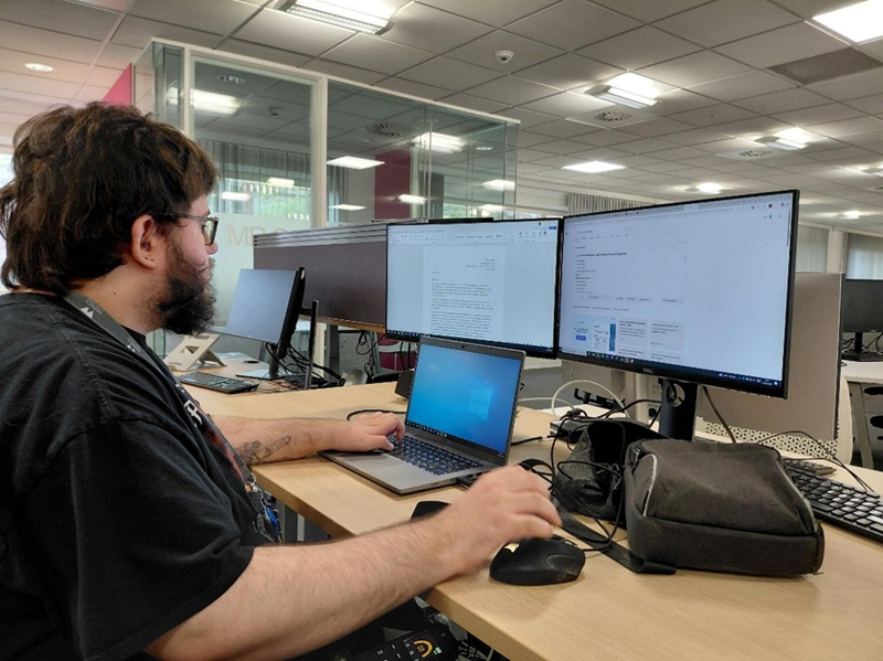 Supported Intern, Ellis, working on a desktop computer on placement at the University of Warwick