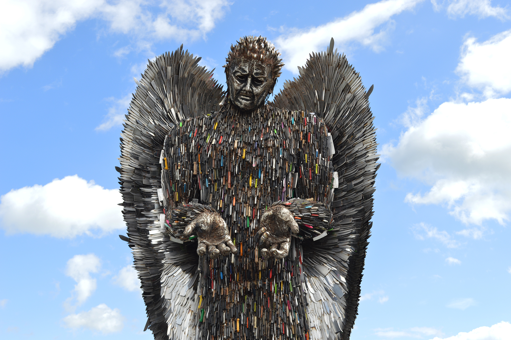 The Knife Angel, a monument made of seized blades, against a blue cloudy sky