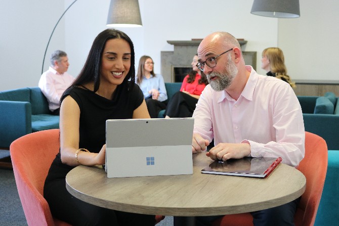 Two people looking at a surface pro screen talking to each other