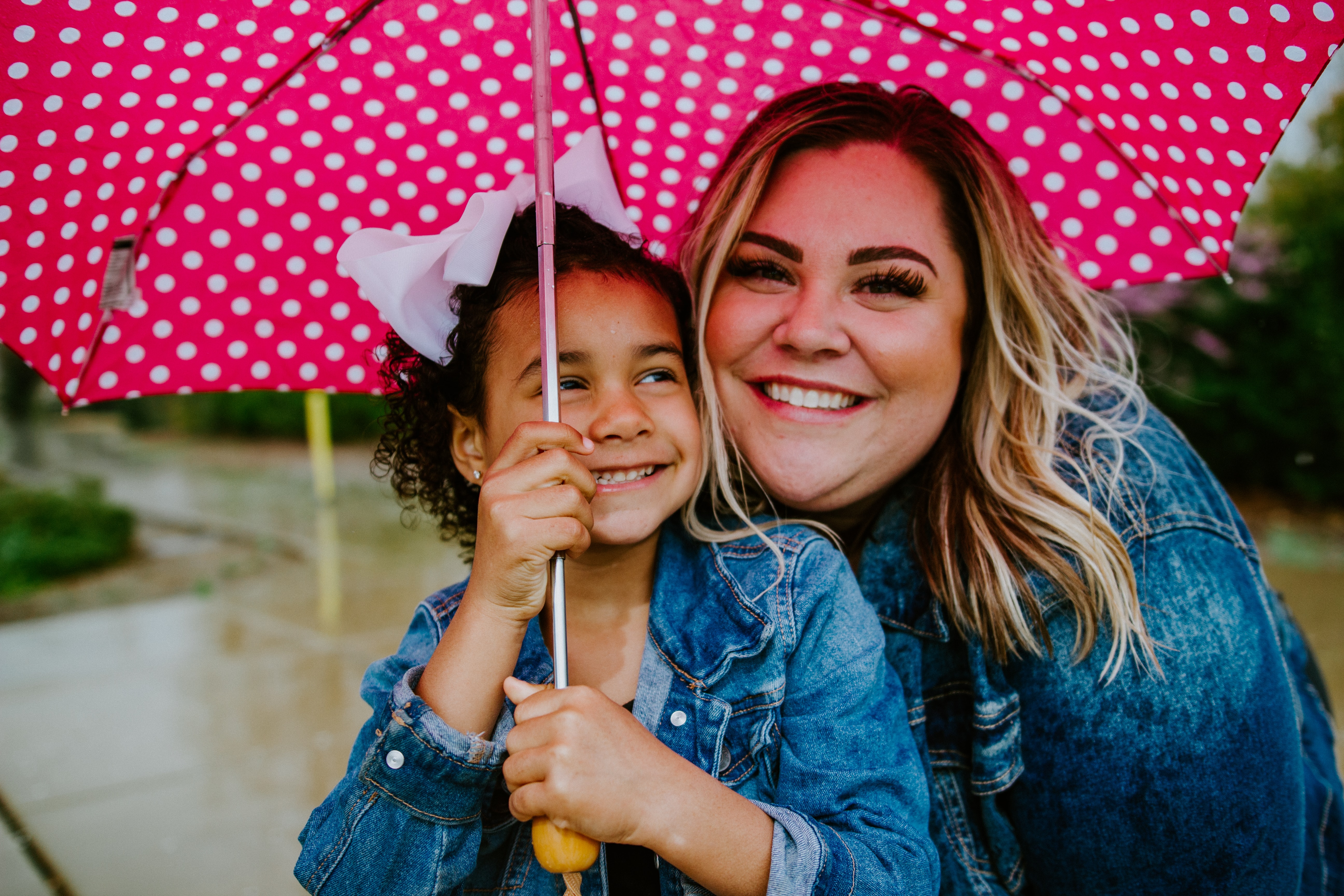 Woman and child smiling under a pink spotty umbrella