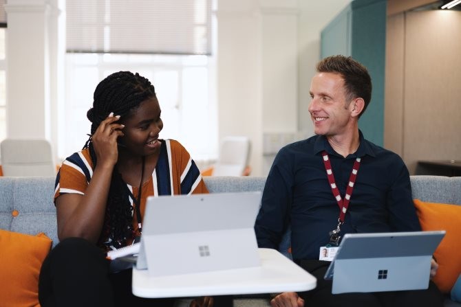 Two people having a chat whilst on their laptops