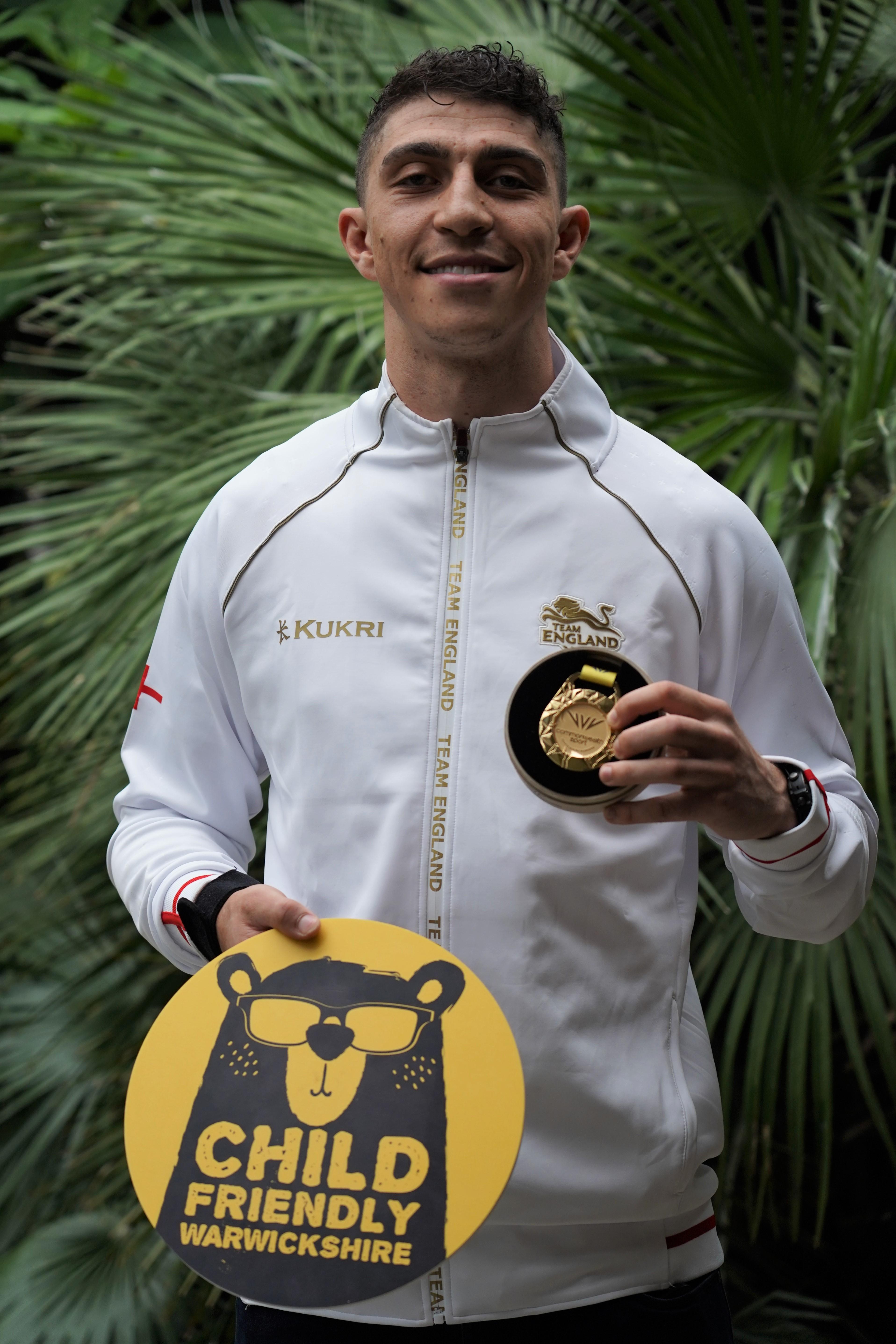 Lewis Williams in his England uniform, holding his gold medal and the CFW logo