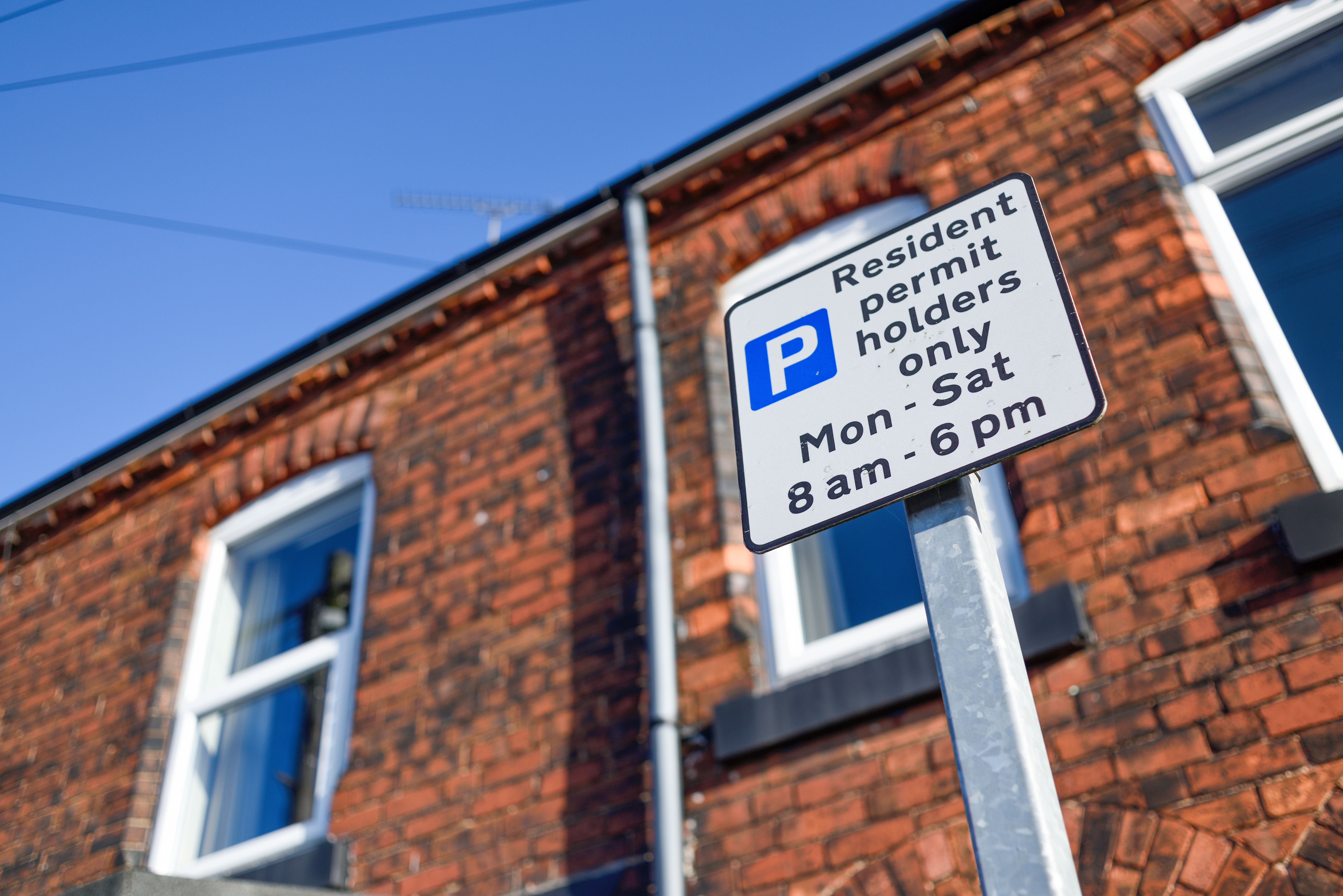 Parking sign outside a row of houses. It reads: Resident permit holders only Mon - Sat 8am - 6pm