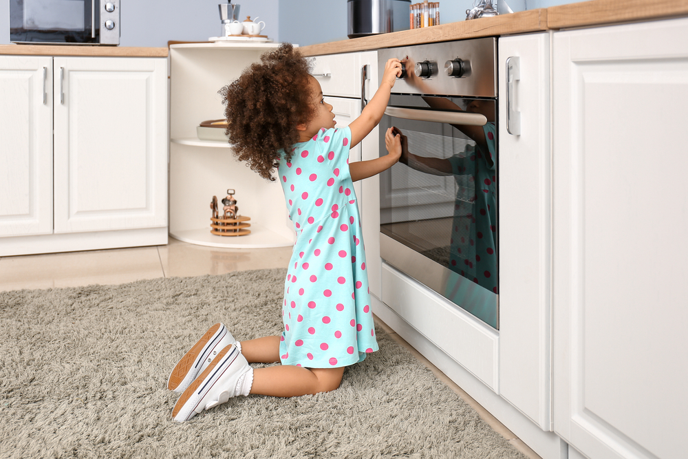 A photo of a child playing with oven in kitchen
