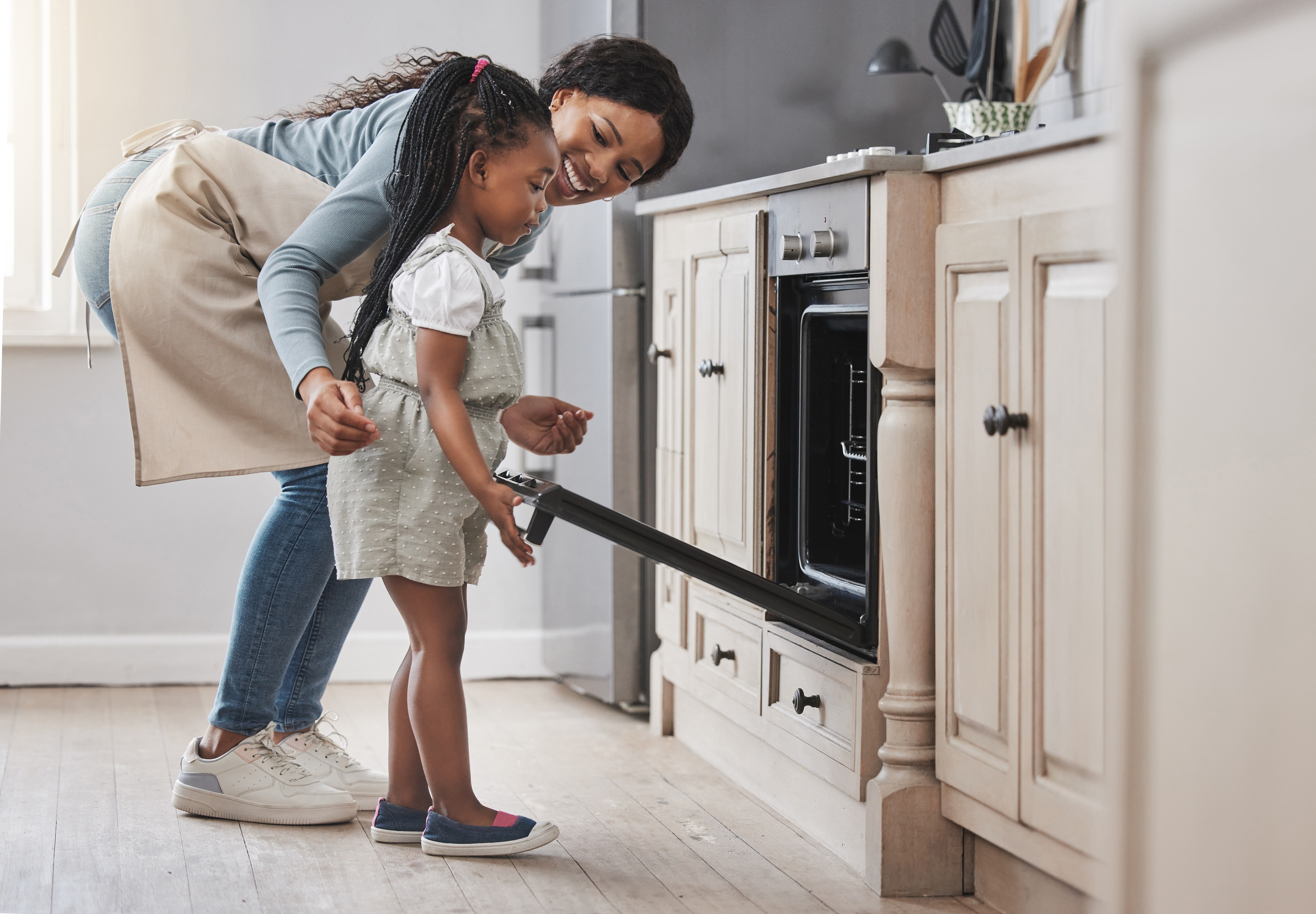 A mother and daughter using the oven in a kitchen