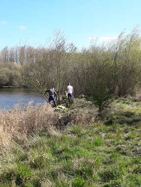 Two volunteers help a Country Parks ranger manage lakeside habitat.