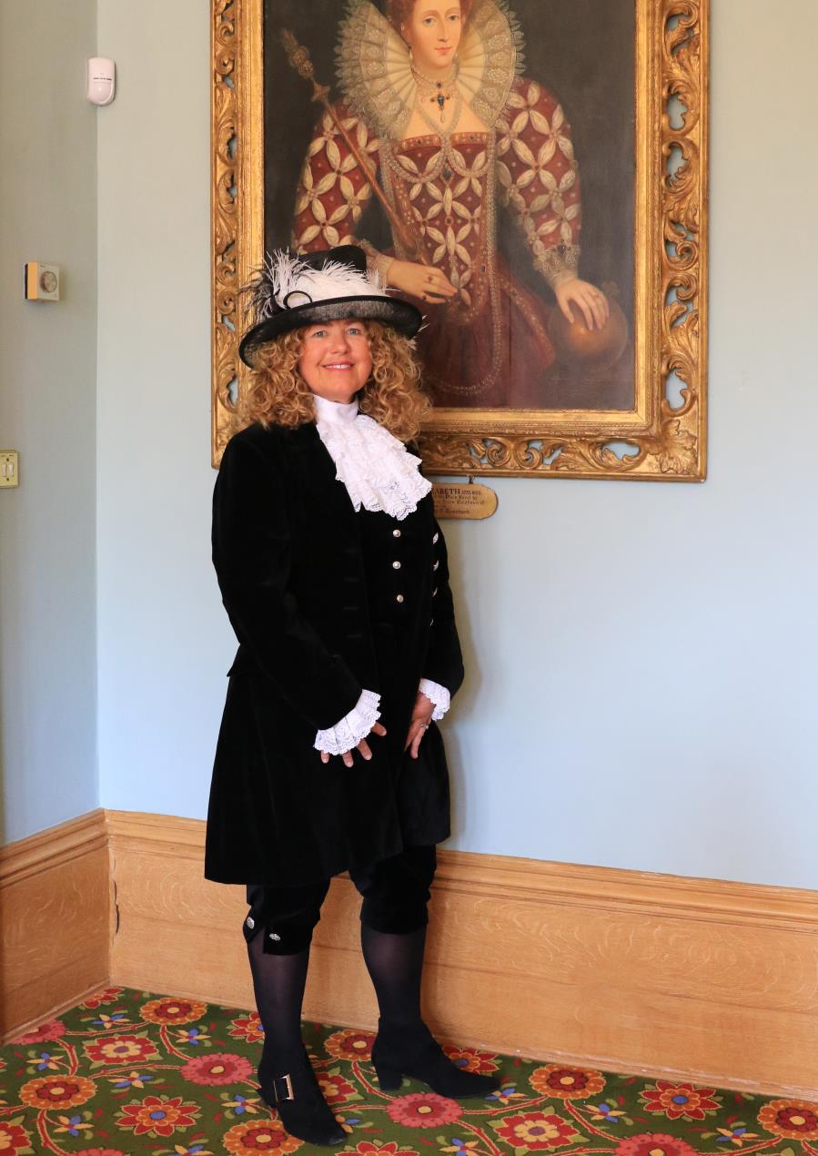 Karen Lynch MBE of Flecknoe, Warwickshire standing in front of portrait.