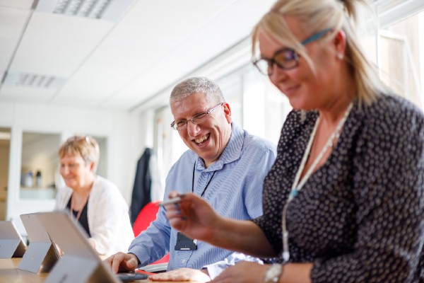 Three people in a meeting with one person laughing